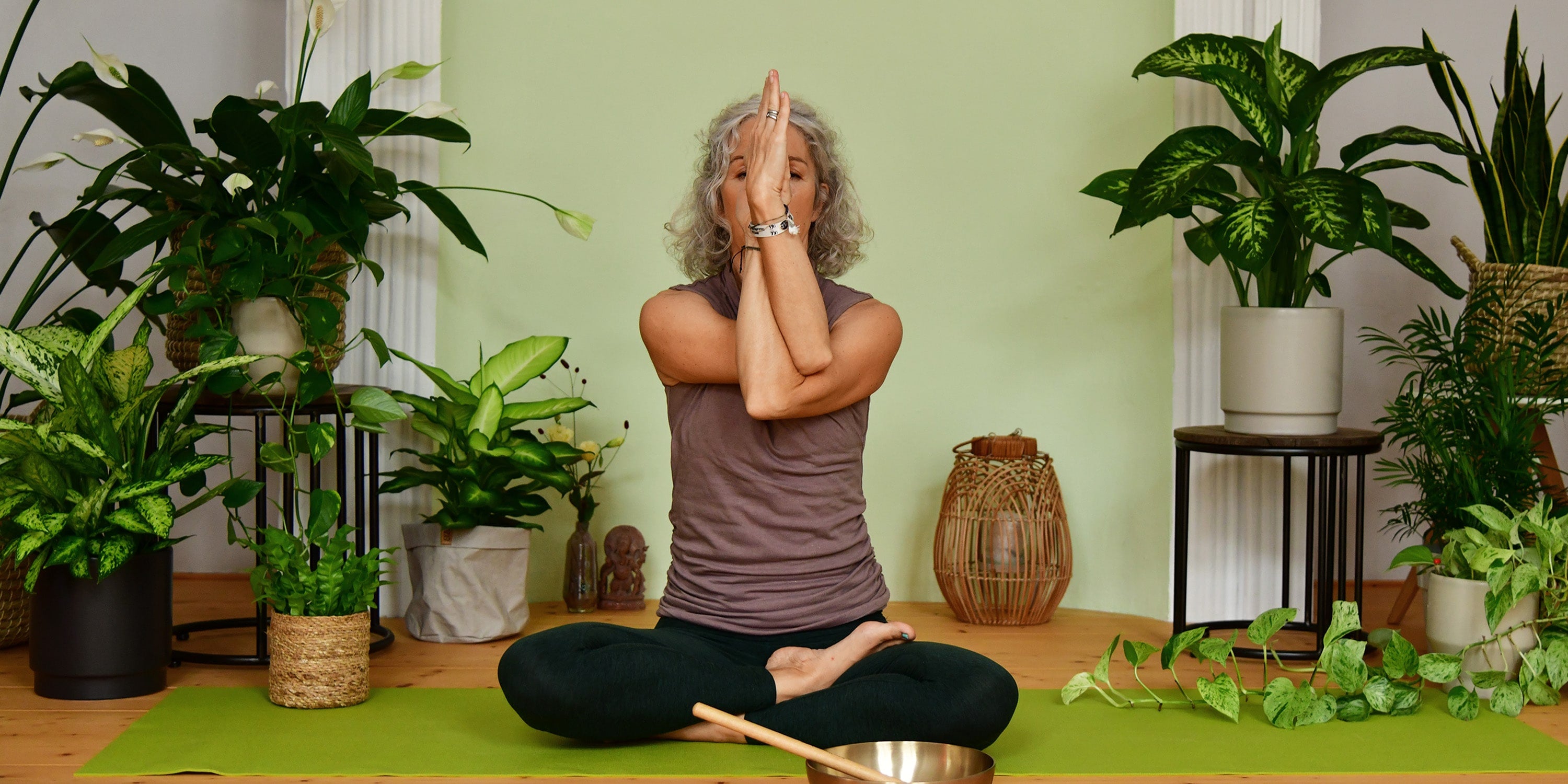 Frau macht Yoga zwischen Zimmerpflanzen Yogastudio